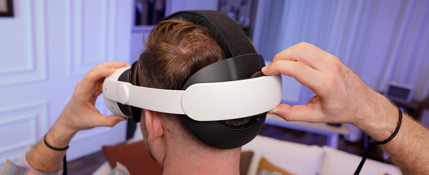 Person using virtual reality headset with MacBook and framed picture in background.